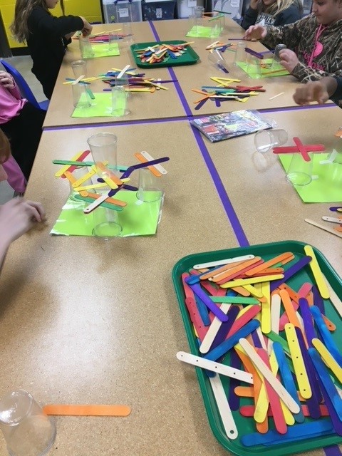 Colored popsicle sticks balanced on top of plastic cups.